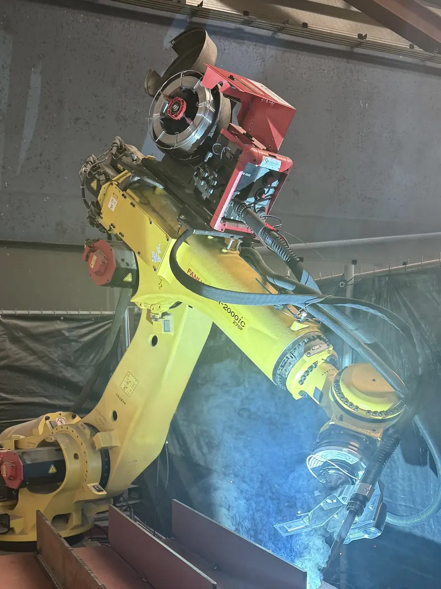 Gele robotarm met een rode freeskop, van dichtbij